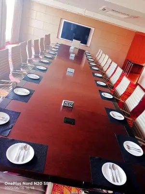 a conference room with a long table with plates on it at Hotel Amaravathi in Mandya