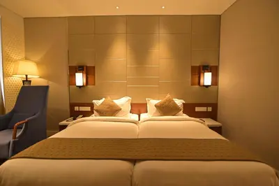 a hotel room with a bed and a chair at Hotel Amaravathi in Mandya