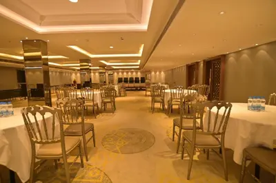 a banquet hall with white tables and chairs in a room at Hotel Amaravathi in Mandya