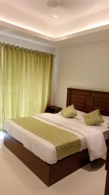 a bedroom with two beds with green curtains at Riviera inn resort in Chillithodu