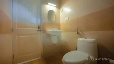 a bathroom with a toilet and a sink at Riviera inn resort in Chillithodu