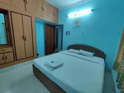a bedroom with a large bed with blue walls at Kavitha House Homestay in Mysore