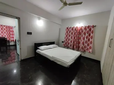 a bedroom with a bed with a red curtain at Royal Wings Apartments in Mysore
