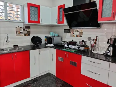 a kitchen with red and white cabinets and a microwave at Royal Wings Apartments in Mysore