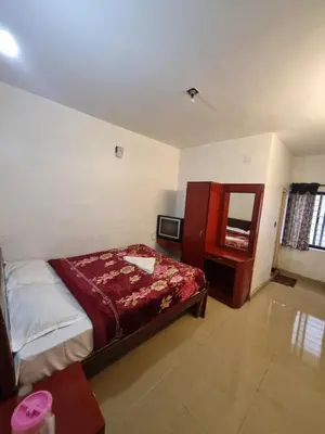 a bedroom with a bed and a dresser and a mirror at Royal Mist in Ooty
