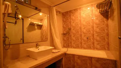 a bathroom with a sink and a shower and a tub at National Residency in Mysore