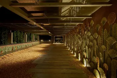 a hallway with a wall of art on the side of a building at MOUNTAIN SHADOWS RESORT Wayanad in Wayanad