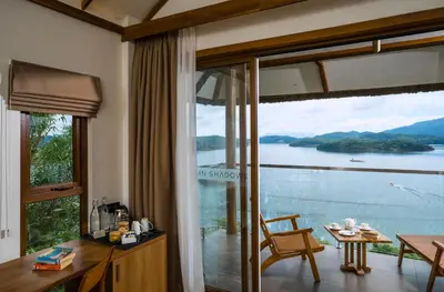 a room with a large window with a view of the water at MOUNTAIN SHADOWS RESORT Wayanad in Wayanad