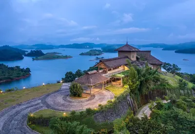 a house on a hill with a view of a lake at MOUNTAIN SHADOWS RESORT Wayanad in Wayanad