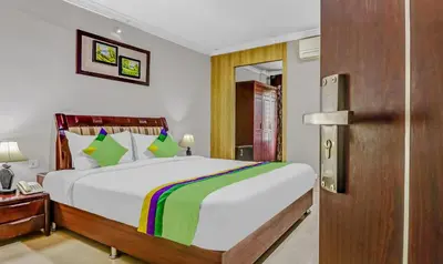 a bedroom with a large bed and a wooden door at Treebo Symphony Hotels And Resorts Angamally in Kizhake Chālakudi