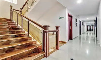 a hallway with wooden stairs and a red door at Treebo Symphony Hotels And Resorts Angamally in Kizhake Chālakudi