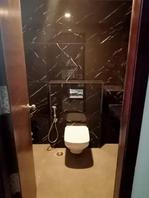 a bathroom with a white toilet and black marble walls at HOTEL VINTAGE CASTLE in Coimbatore