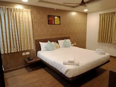 a bedroom with a large bed with white sheets at HOTEL VINTAGE CASTLE in Coimbatore