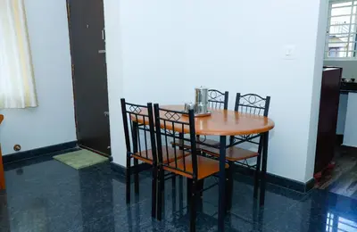 a wooden table and chairs in a room at The Coorg Heaven in Madikeri