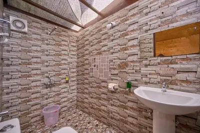 a bathroom with a sink and a stone wall at De Rock Jungle Living Resort in Coonoor