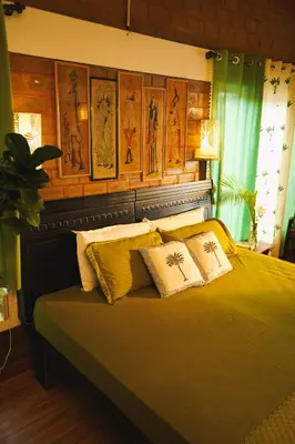 a bedroom with a bed with yellow sheets and pillows at De Rock Jungle Living Resort in Coonoor