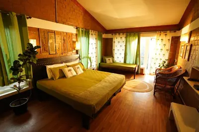 a bedroom with a large bed in a room with green curtains at De Rock Jungle Living Resort in Coonoor
