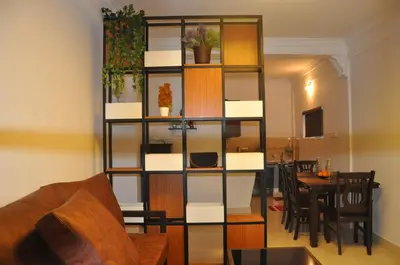 a living room with a book shelf and a table at Little House Ooty in Ooty