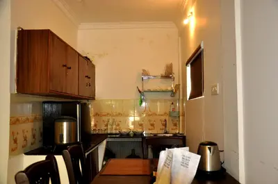 a small kitchen with wooden cabinets and a table at Little House Ooty in Ooty