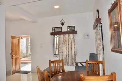a dining room with a table and chairs and a window at Little House Ooty in Ooty