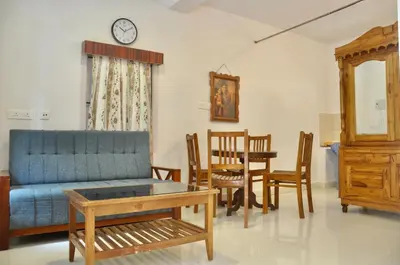 a living room with a blue couch and a table at Little House Ooty in Ooty