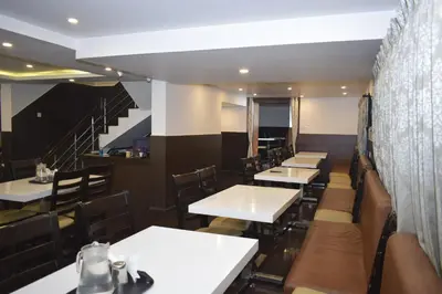 a restaurant with tables and chairs and a staircase at The Baron in Ooty