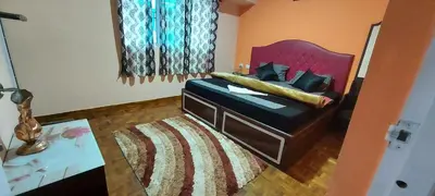 a bedroom with a bed with a red headboard and a rug at IMPERIAL COTTAGE, HILL BUNK OOTY in Ooty