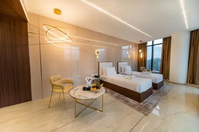 a hotel room with two beds and a table at Fezinn Hotel - Best Wayanad Hotel in 2024 in Kozhikode