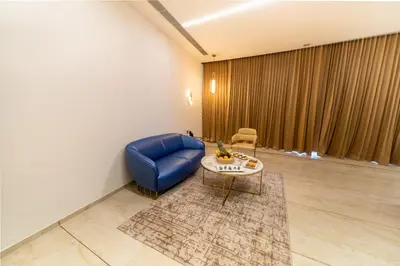 a living room with a blue chair and a table at Fezinn Hotel - Best Wayanad Hotel in 2024 in Kozhikode
