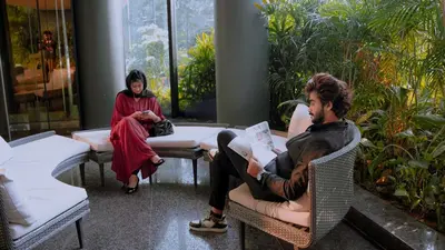 a man and a woman sitting in chairs in a room at Fezinn Hotel - Best Wayanad Hotel in 2024 in Kozhikode
