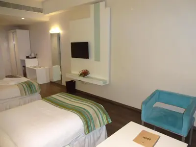 a hotel room with two beds and a blue chair at The Arcadia Coimbatore Airport in Coimbatore