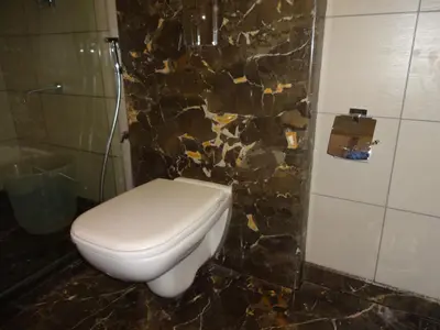 a bathroom with a toilet and a stone wall at The Arcadia Coimbatore Airport in Coimbatore