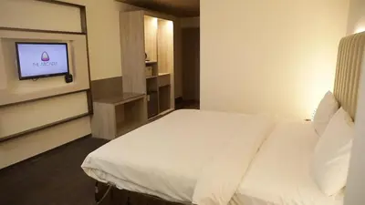 a bedroom with a white bed and a television at The Arcadia Coimbatore Airport in Coimbatore