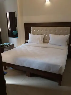 a bedroom with a large bed with white sheets and pillows at ADVAITHA RESIDENCY in Mysore