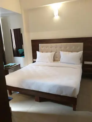 a bedroom with a large bed with white sheets and pillows at ADVAITHA RESIDENCY in Mysore