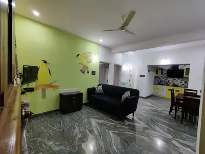 a living room with a couch and birds painted on the wall at Vogel's Nest in Mysore