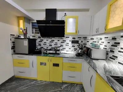 a kitchen with yellow and white cabinets and a sink at Vogel's Nest in Mysore