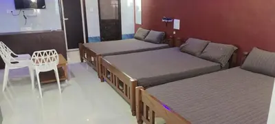 a room with three beds and a chair and a table at C M HOTEL NEW in Wodapatti