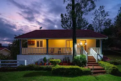 a small yellow house with a porch and stairs at StayVista at Casa Pinnacle - Pet Friendly Home with Lawn in Coonoor