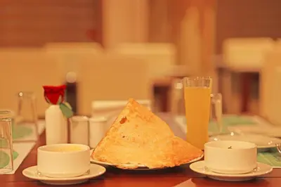 a table with a piece of bread and a glass of orange juice at Krishnavalsam Regency in Guruvāyūr