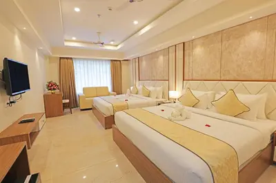a hotel room with two beds and a television at Krishnavalsam Regency in Guruvāyūr