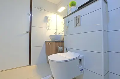 a white bathroom with a toilet and a sink at Krishnavalsam Regency in Guruvāyūr