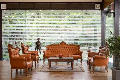a living room with leather furniture and a large window at Au Revoir Wellness Resort, Malampuzha in Palakkad