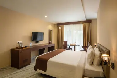 a hotel room with a bed and a television at Au Revoir Wellness Resort, Malampuzha in Palakkad
