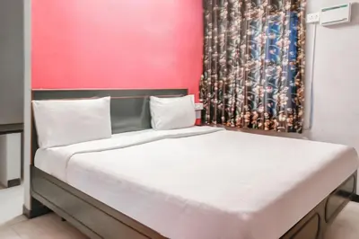 a bed in a room with a red wall at Hotel O Kota Lodge in Coimbatore