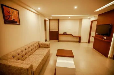 a living room with a couch and a tv at Nesma Palace in Kannur