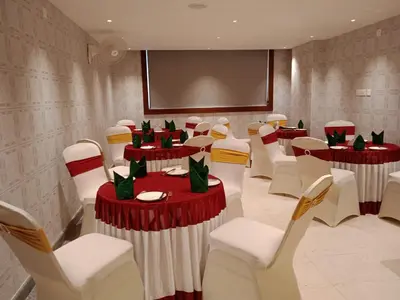a conference room with red and white tables and chairs at Nesma Palace in Kannur