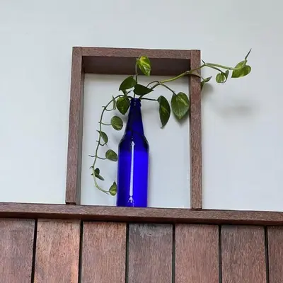 a blue bottle with a plant in it on a shelf at Casita Greens in Kondotti
