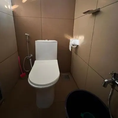 a bathroom with a white toilet in a stall at Casita Greens in Kondotti