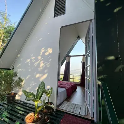 a room with a bed and a window on a balcony at Casita Greens in Kondotti